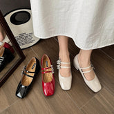 A collection of women's flat shoes in black, red, and pink colors, displayed in a mirror with a person standing in the foreground wearing one of the shoes.