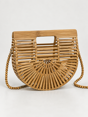 A light brown bamboo handbag with a semi-circular slatted design, a top handle cutout, and a matching beaded shoulder strap, shown on a light gray background.